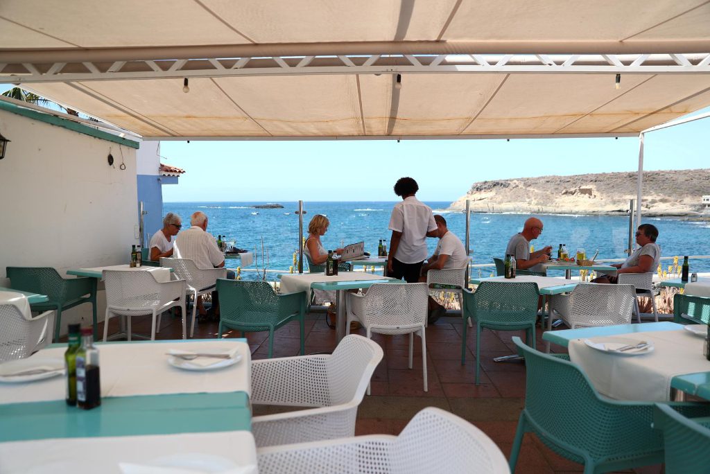 Waiter Yamilca from Cuba attends tourists in a terrace of an almost empty restaurant "Celso" at La Caleta beach in Adeje, in the Spanish Canary Island of Tenerife, Spain March 5, 2020. Nearby island La Gomera is testing a coronavirus tracing app for visitors.